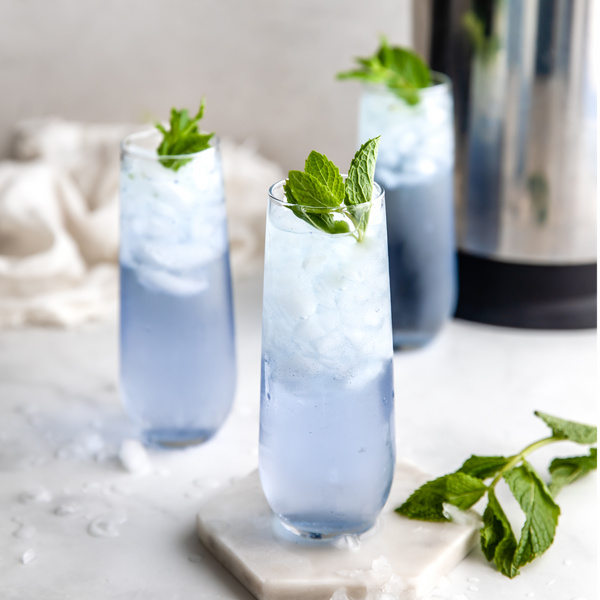 glasses of blue mojitos with fresh mint leaves