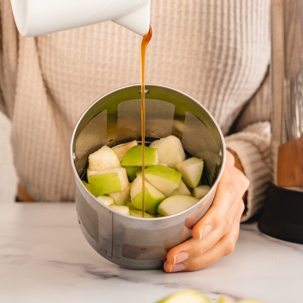 apples in a filter basket with vegan caramel being poured 
