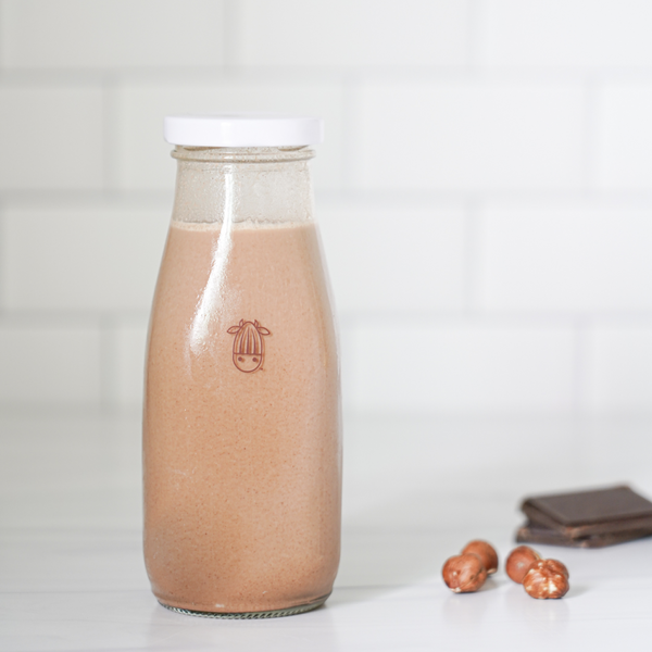 vegan chocolate hazelnut creamer in an almond cow glass bottle