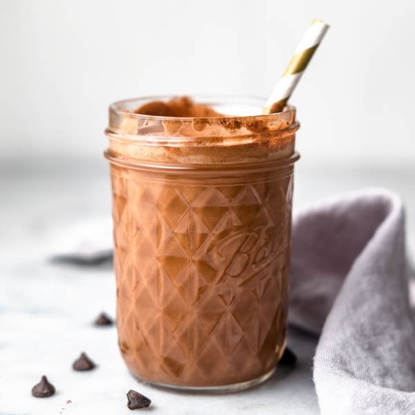 plant-based chocolate  milk in a glass with a straw made in an Almond Cow