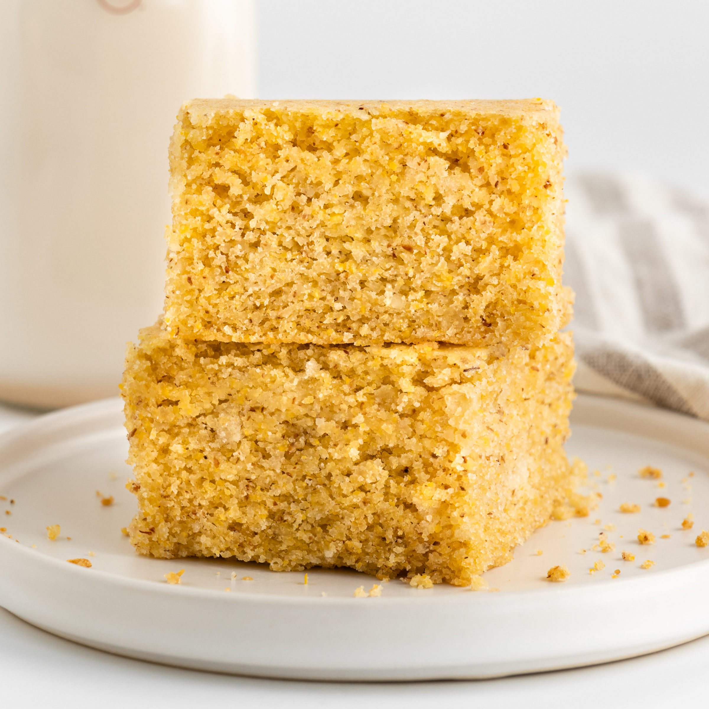 vegan cornbread on a plate with a glass bottle of plant-based milk