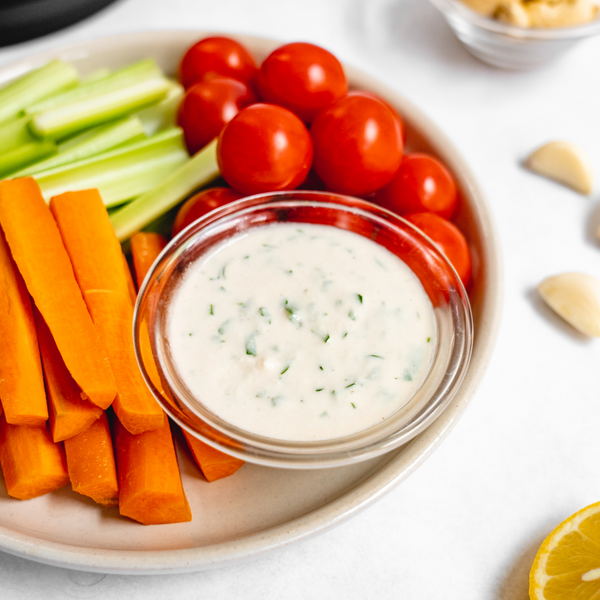 vegan garden ranch dressing on a plate with carrots, tomatoes, and celery