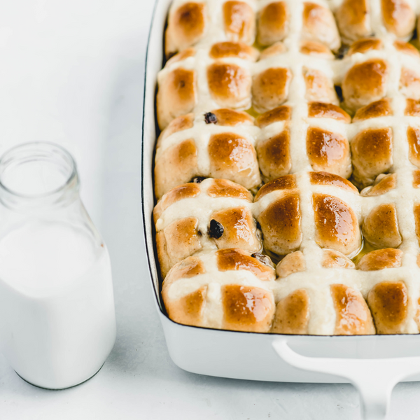 vegan hot cross buns with a glass of plant-based milk