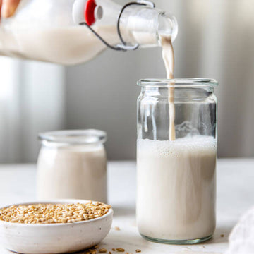 homemade oat milk being poured into a glass