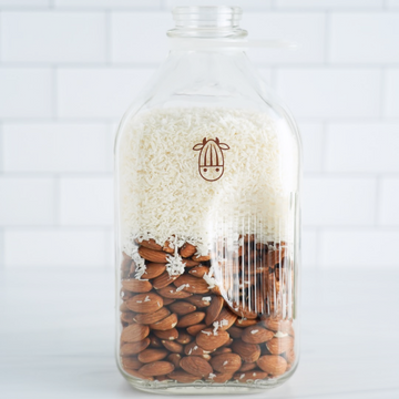 Pro Coconut shreds and almonds in a glass milk jug 