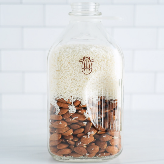 Pro Coconut shreds and almonds in a glass milk jug 