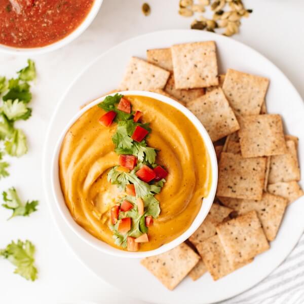 a bowl of vegan cashew pulp queso and vegan crackers