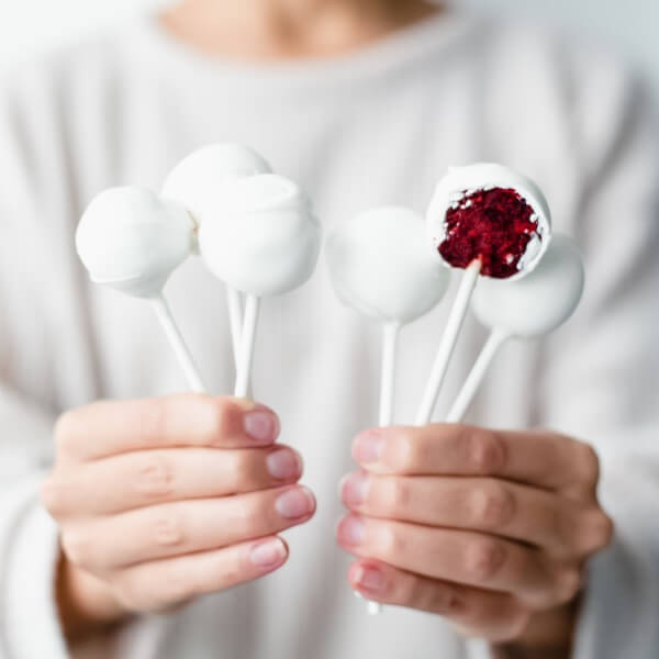 a person holding 6 vegan Red Velvet Cake Pops