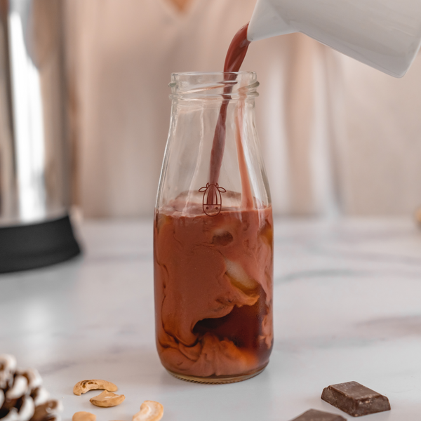 vegan, plant-based red velvet creamer being poured into an almond cow glass bottle