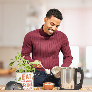 A photo of a man happily using his almond cow to create dopamine-boosting recipes.