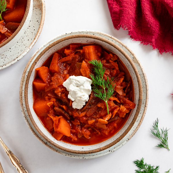 vegan borscht in a bowl topped with vegan sour cream and dill
