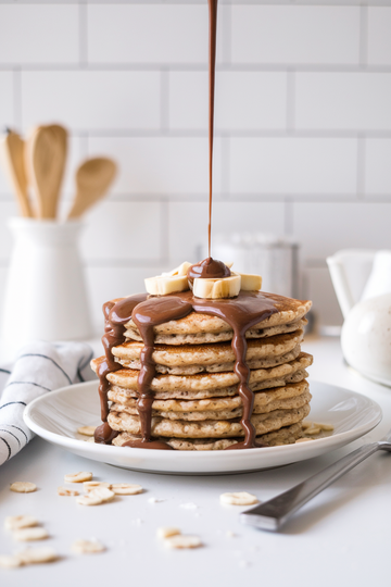 A stack of homemade oat pulp pancakes with hazelnut spread drizzled on top.