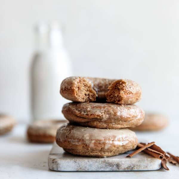 stack of vegan Maple Glazed Donuts with a glass of plant-based milk