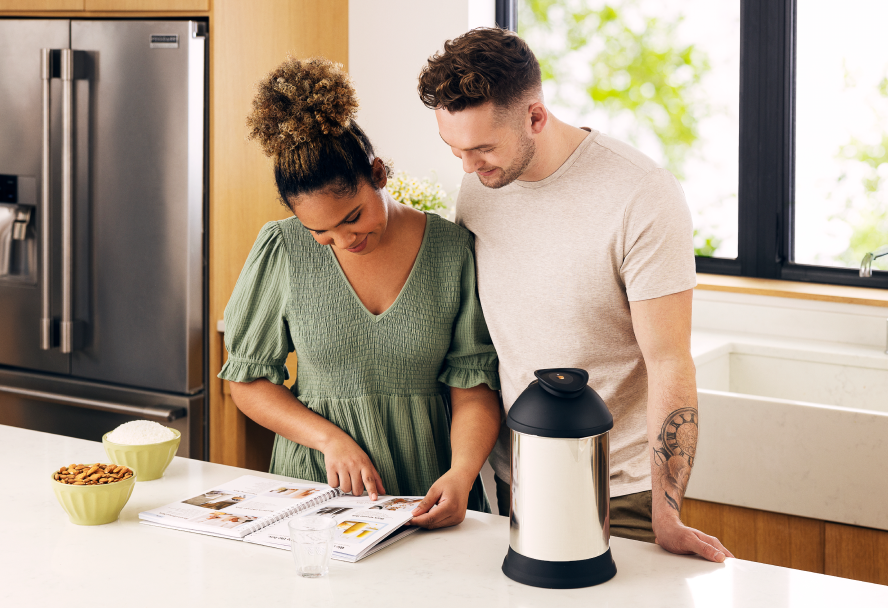Woman and man reading almond cow recipe book in kitchen 