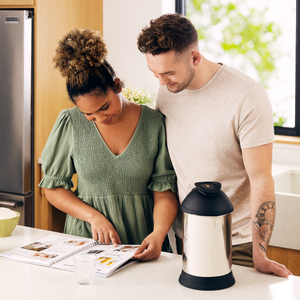 Woman and man reading almond cow recipe book in kitchen 
