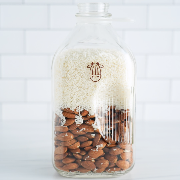 Pro Coconut shreds and almonds in a glass milk jug
